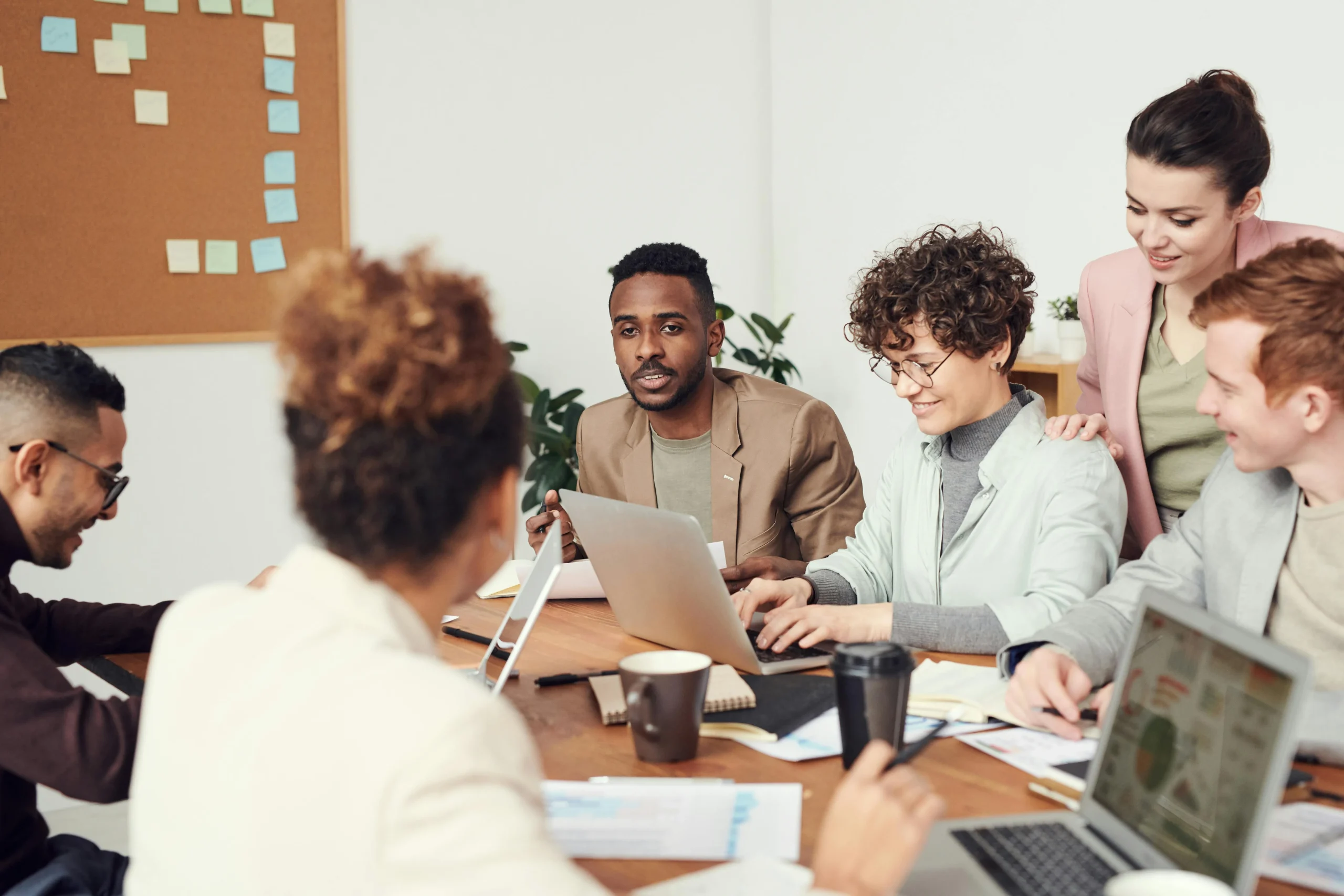 Several diverse co-workers gather around a conference table in discussion.