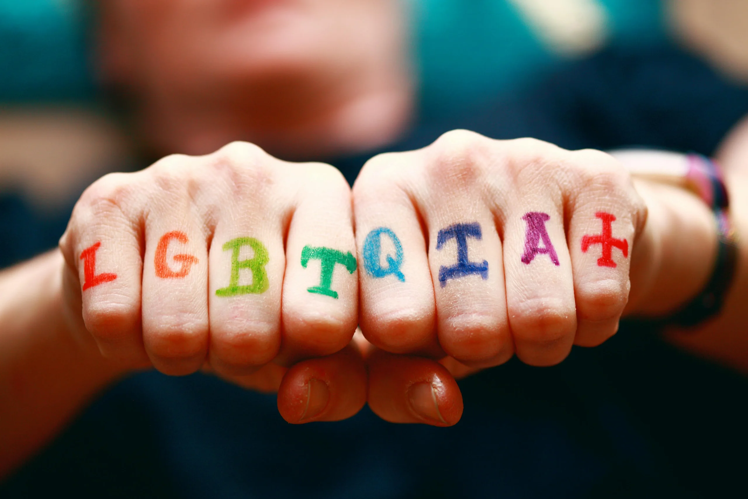 Hands with LGBTQIA tattoo on the fingers