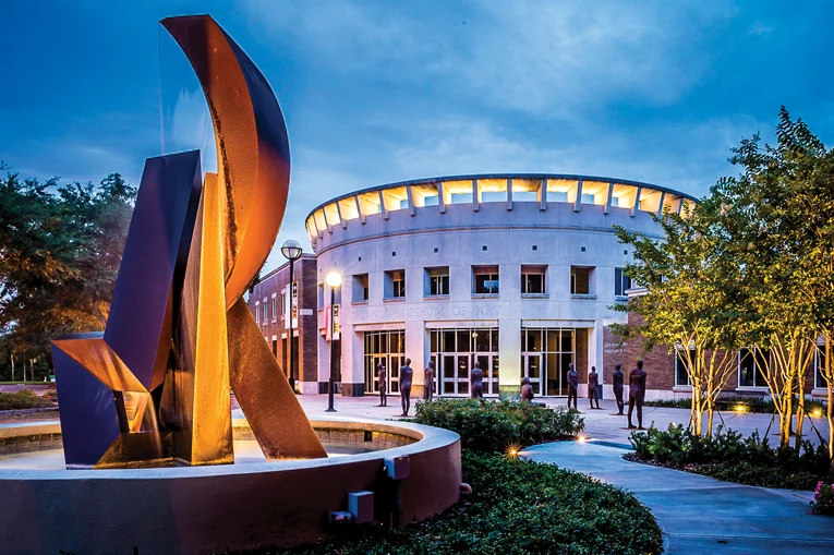 Orlando Museum of Art at dusk. A pale, round building with a courtyard featuring an abstract sculpture.