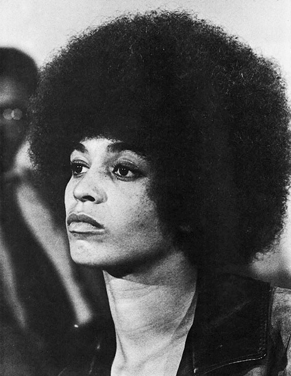 A black and white photograph of Angela Davis, a young woman with a black afro.