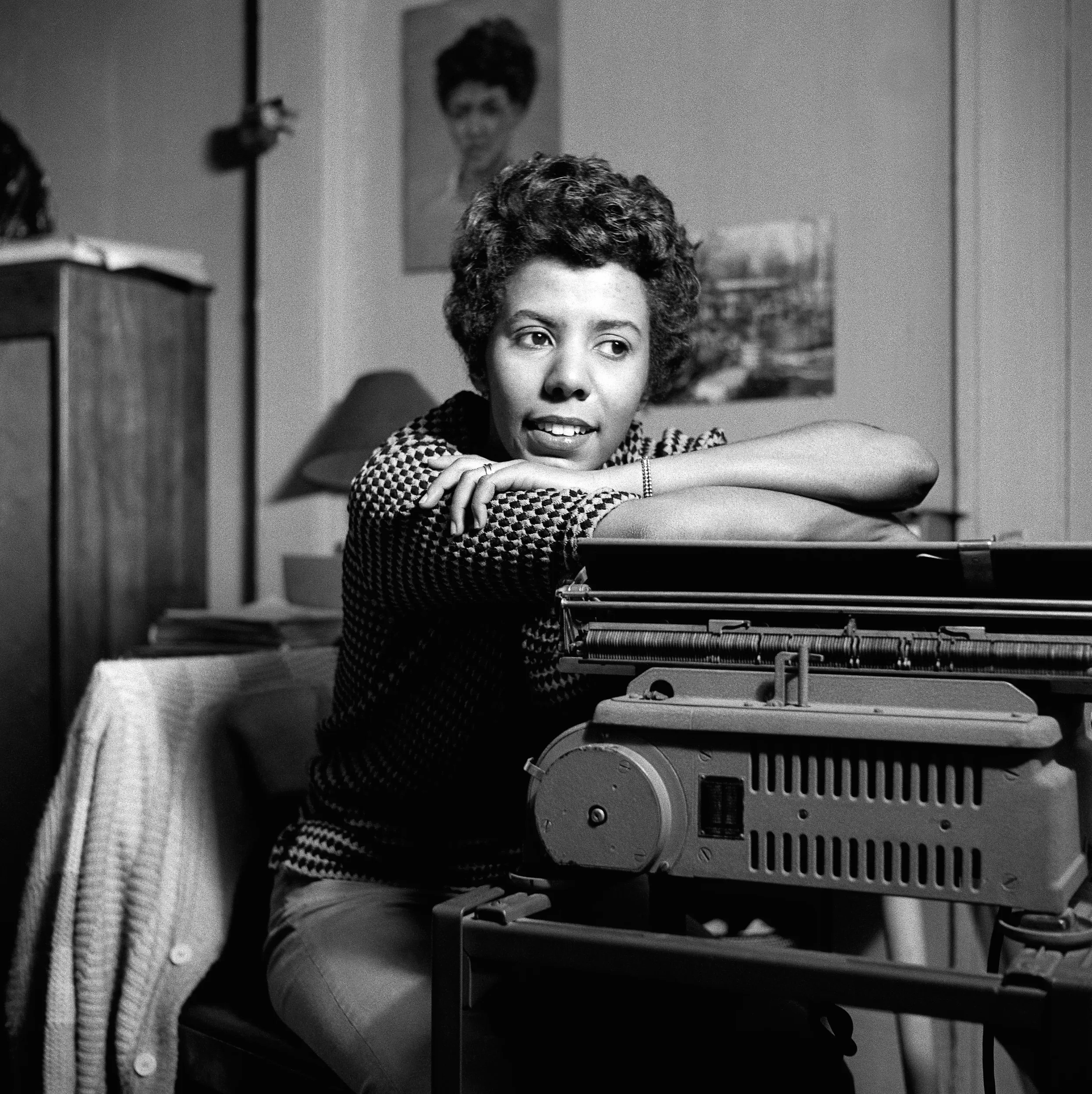 Black and white photograph of Lorraine Hansberry, a young woman with short hair, leaning on a typewriter