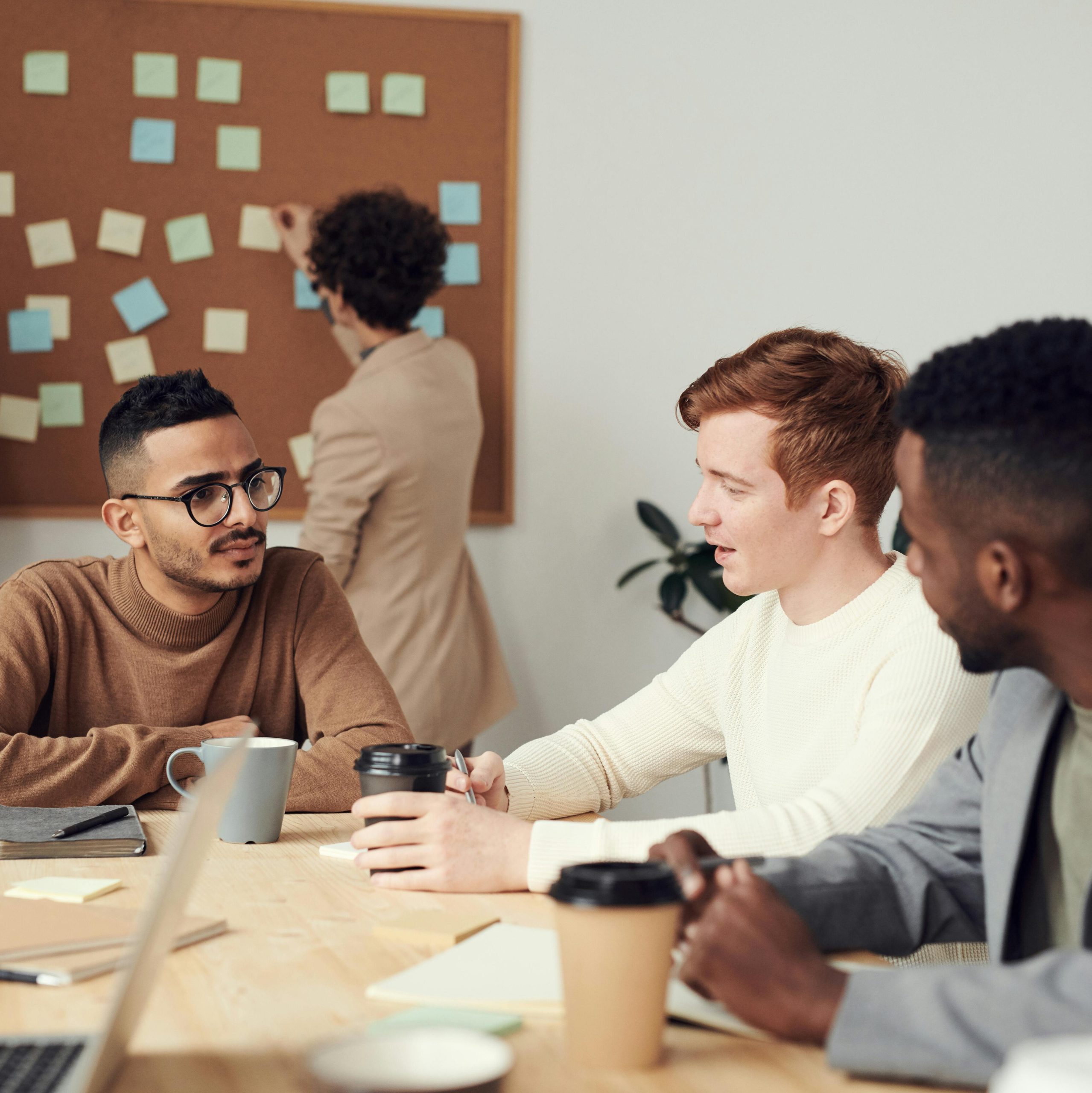 Three co-workers speak together in a conference room.